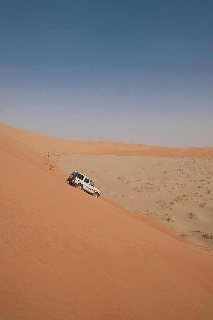 UAE, Abu Dhabi, Four wheel drive going down steep sand dune; Liwa