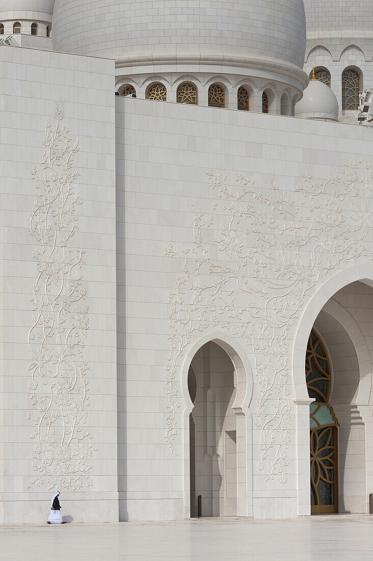 Arabischer Mann geht durch den Innenhof der Sheikh Zayed Grand Mosqueabu Dhabi, Vereinigte Arabische Emirate