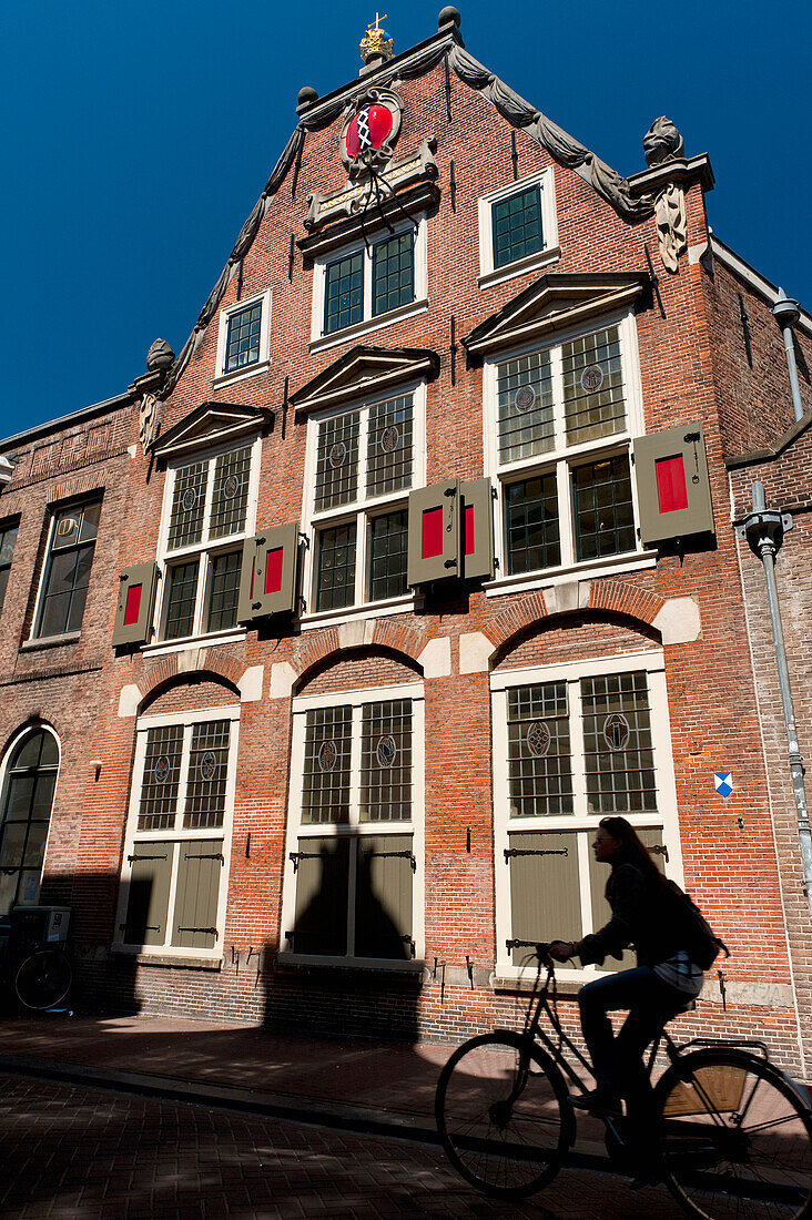 Silhouette eines Radfahrers, der an einem traditionellen holländischen Haus vorbeifährt,Amsterdam, Holland.