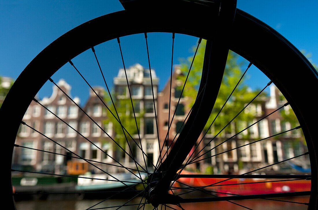 Silhouette eines Fahrrads vor einer Gracht und traditionellen GiebelhäusernSamsterdam, Holland.