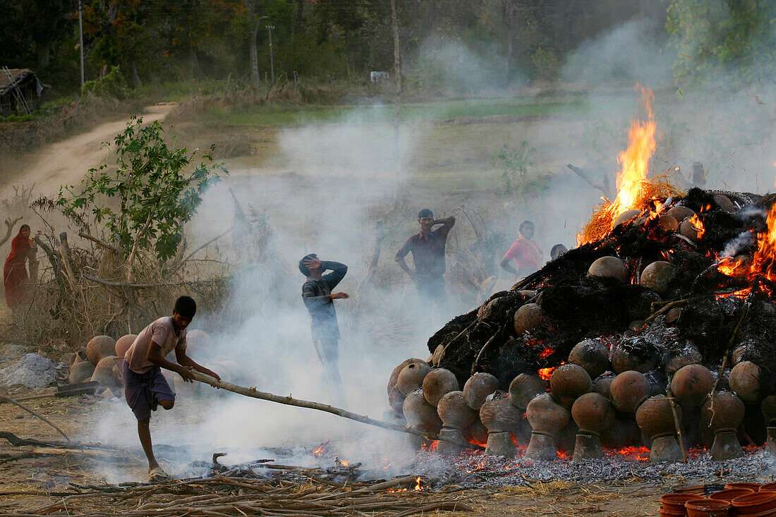 Ein Feuer, das Gegenstände verbrennt und Rauch erzeugt, Töpferdorf; Madhya Pradesh, Indien
