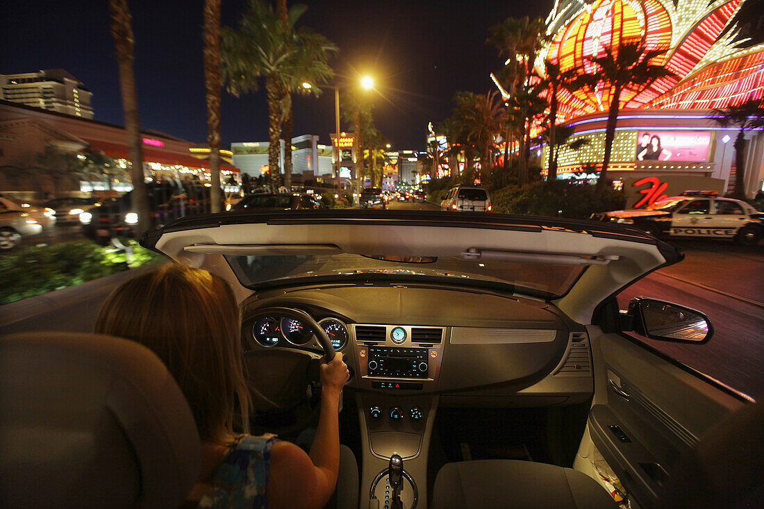 Usa, Nevada, Junge Frau fährt mit ihrem Cabrio den Las Vegas Boulevard ( Strip ) in Las Vegas bei Nacht unter Neonlichtern entlang; Las Vegas