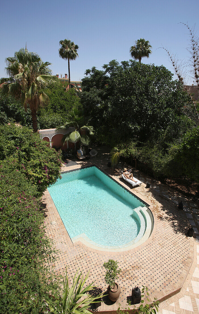 WOMAN SUNBATHING IN RIAD GARDEN'xA; MARRAKESH MOROCCO