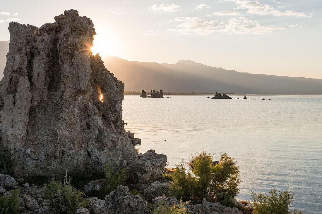 The sun peeks from behind a tufa at Mono Lake South Tufa.; Mono Lake, California, United States of America