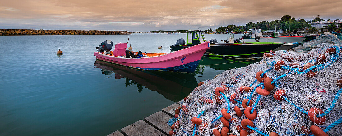 Motorboats and fishing boats moored to the dock, piled with fishing nets in the harbor in Sainte Rose on Basse-Terre; Guadeloupe, French West Indies