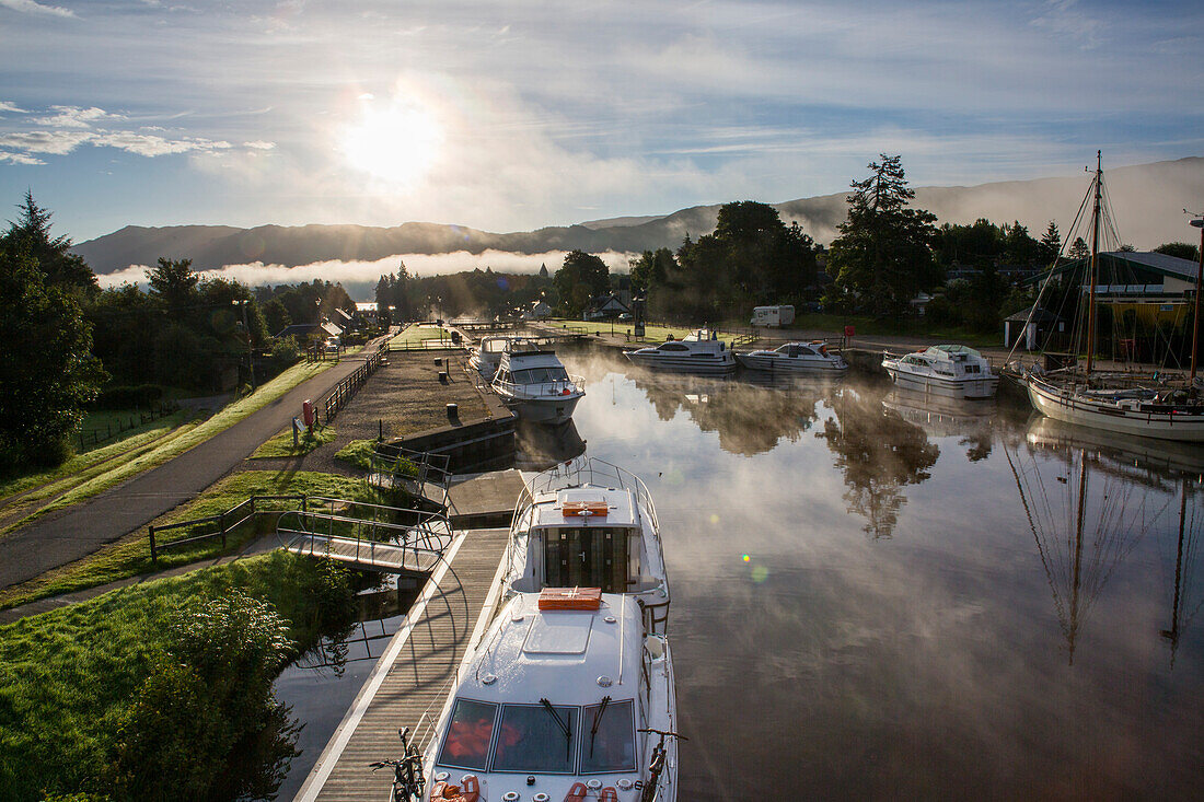 As the sun rises, fog lifts above Loch Ness along the Caledonian Canal at Fort Augustus, Scotland; Fort Augustus, Scotland