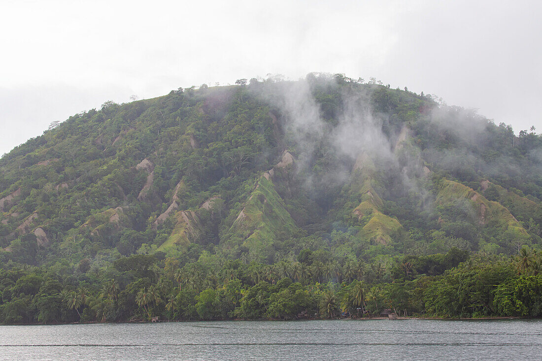 Dampf, der aus dem Dschungel von Dobu Island auf den D'Entrecasteaux-Inseln, Papua-Neuguinea, aufsteigt; Dobu Island, D'Entrecasteaux-Inseln, Papua-Neuguinea