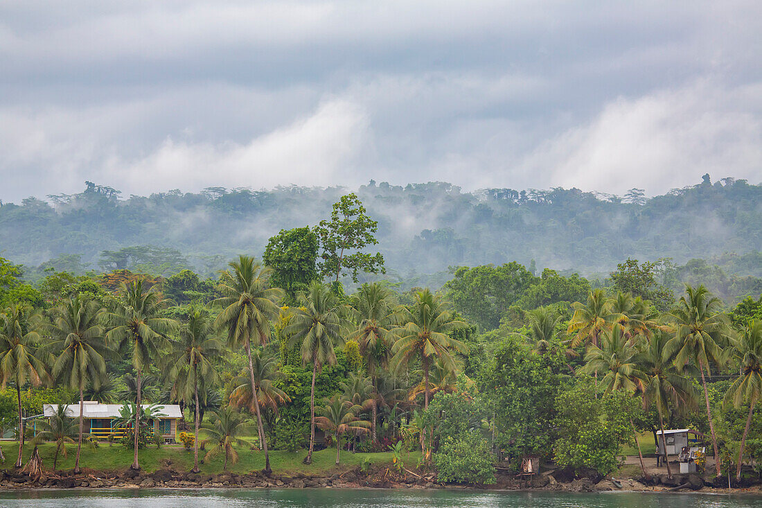Dschungel und Küstendorf Siboma mit Hütten auf Stelzen auf Lababia Island, Huon Gulf; Siboma, Provinz Morobe, Papua-Neuguinea