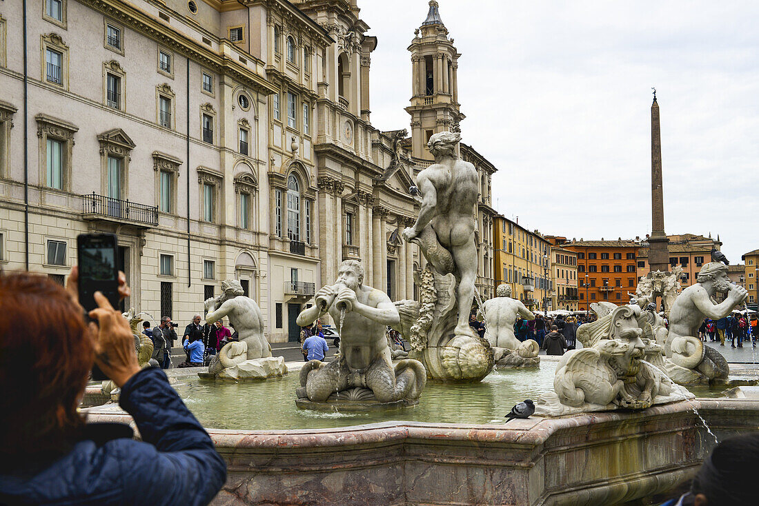 Blick von hinten auf einen Touristen, der die Fontana del Moro auf der Piazza Navona fotografiert; Rom, Latium, Italien