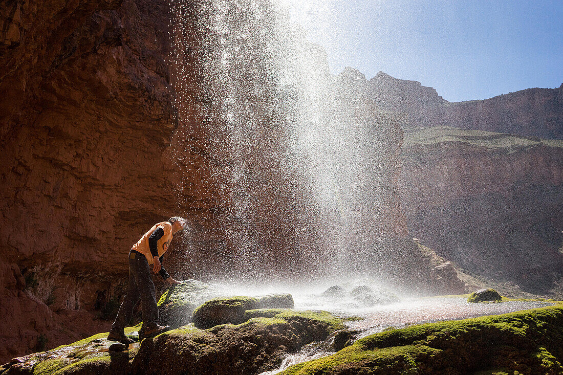 Ein Wanderer benetzt sein Gesicht unter den Ribbon Falls am North Kaibab Trail; Grand Canyon National Park, Arizona