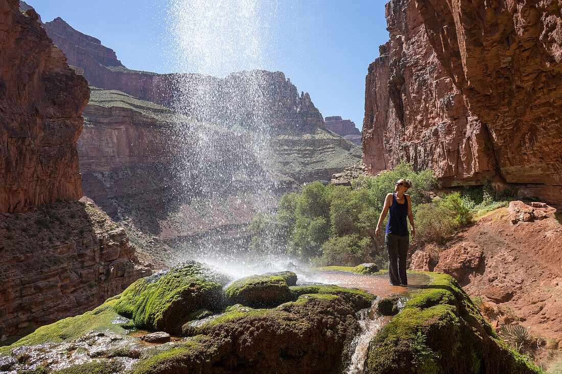 A hiker stands under Ribbon Falls off North Kaibab Trail.; Grand Canyon National Park, Arizona