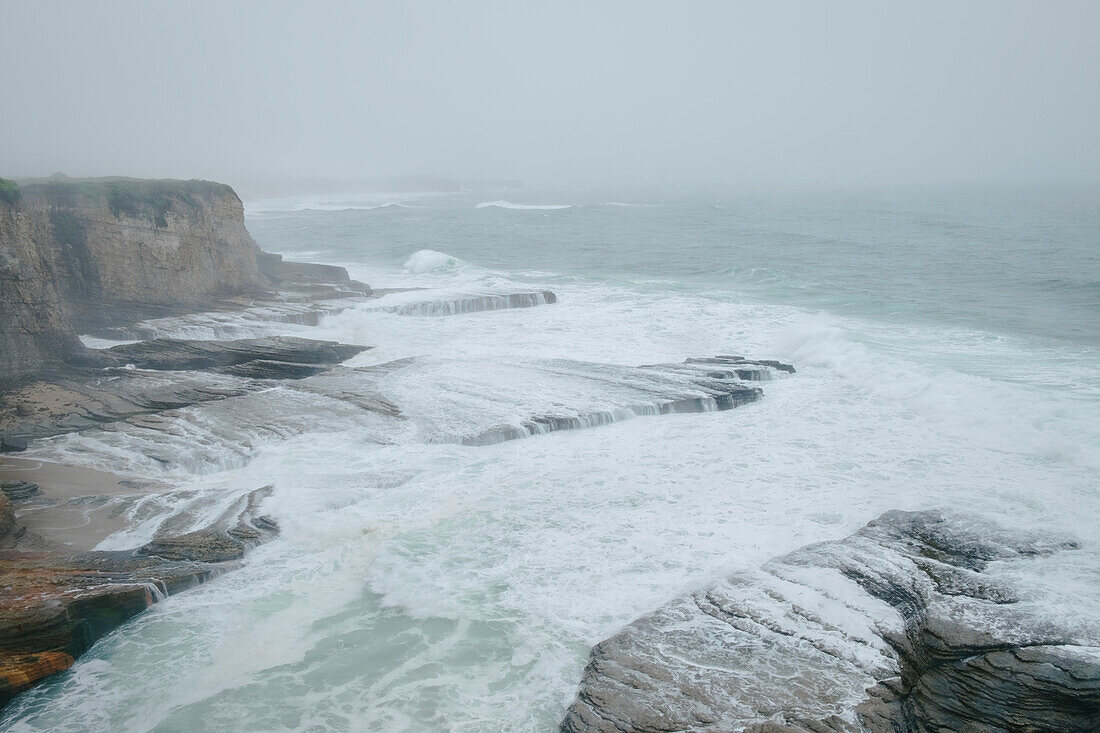 Große Sturmbrandung mit Wellen, die gegen den Felsvorsprung entlang der felsigen Küste der Central Coast krachen; Santa Cruz, Kalifornien, Vereinigte Staaten von Amerika