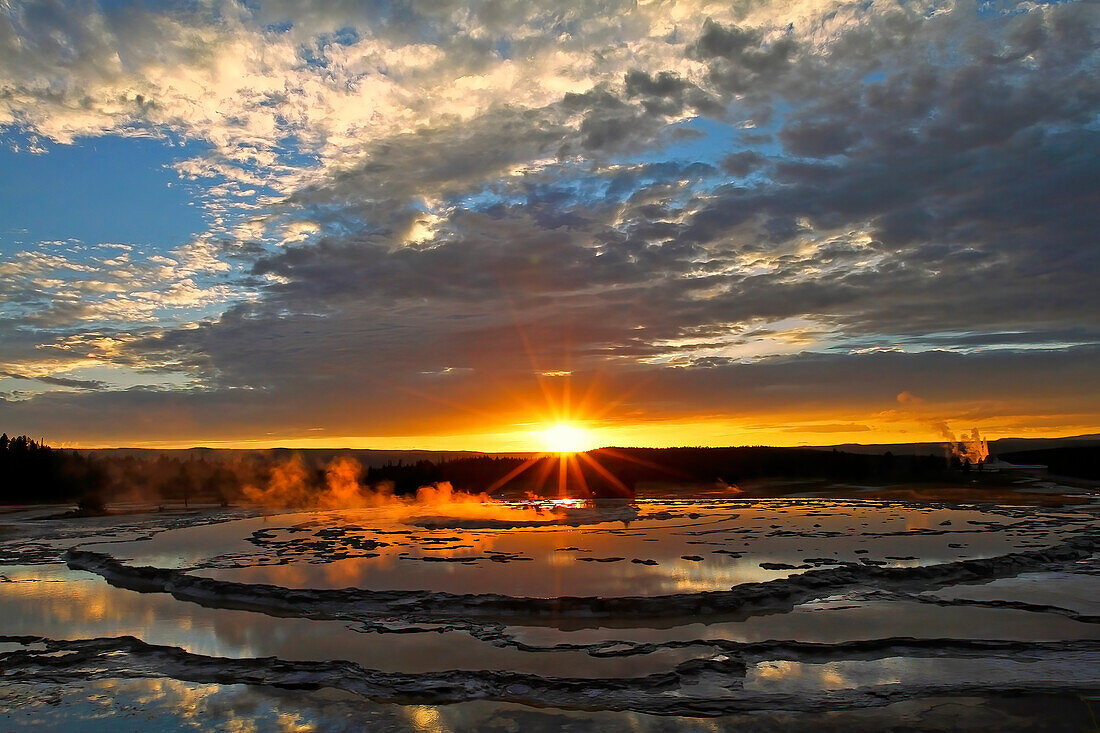 Dampfendes Becken mit geothermischem Wasser in der Nähe des berühmten Geysirs Old Faithful bei Sonnenuntergang im Yellowstone National Park; Teton County, Wyoming, Vereinigte Staaten von Amerika