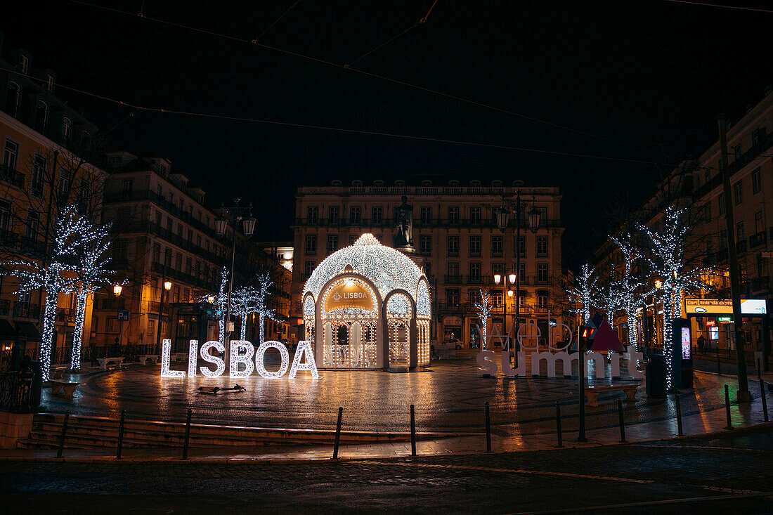 Weihnachtsbeleuchtung an einem Pavillon mit einem beleuchteten Lisboa-Schild auf einem Stadtplatz in den Vierteln Chiado und Bairro Alto; Lissabon, Estremadura, Portugal
