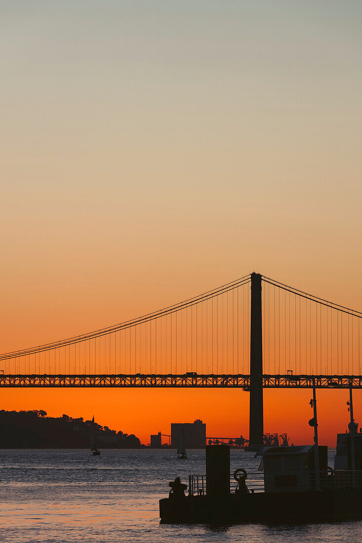 Silhouette der Brücke 25 de Abril über den Tejo, die Lissabon und Almada verbindet, bei Sonnenuntergang; Lissabon, Estremadura, Portugal