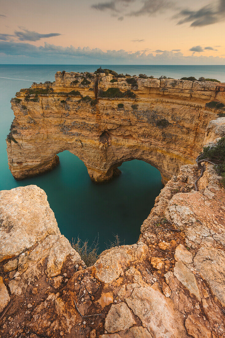 Iconic rock formation, Arcos Naturais, Heart of the Algarve, and the turquoise water of the Atlantic Ocean at Praia da Marinha along the Atlantic coast in Caramujeira, part of the Lagoa Municipality, at sunset; Algarve, Faro District, Portugal