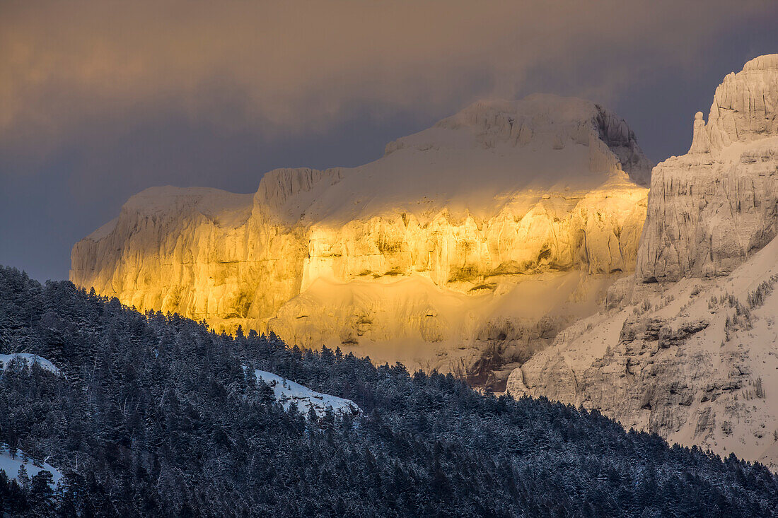 Coated with snow and illuminated with the warm light of sunset, Amphitheater Mountain glows with a wonderful golden color in the Absaroka Range, Yellowstone National Park; Wyoming, United States of America