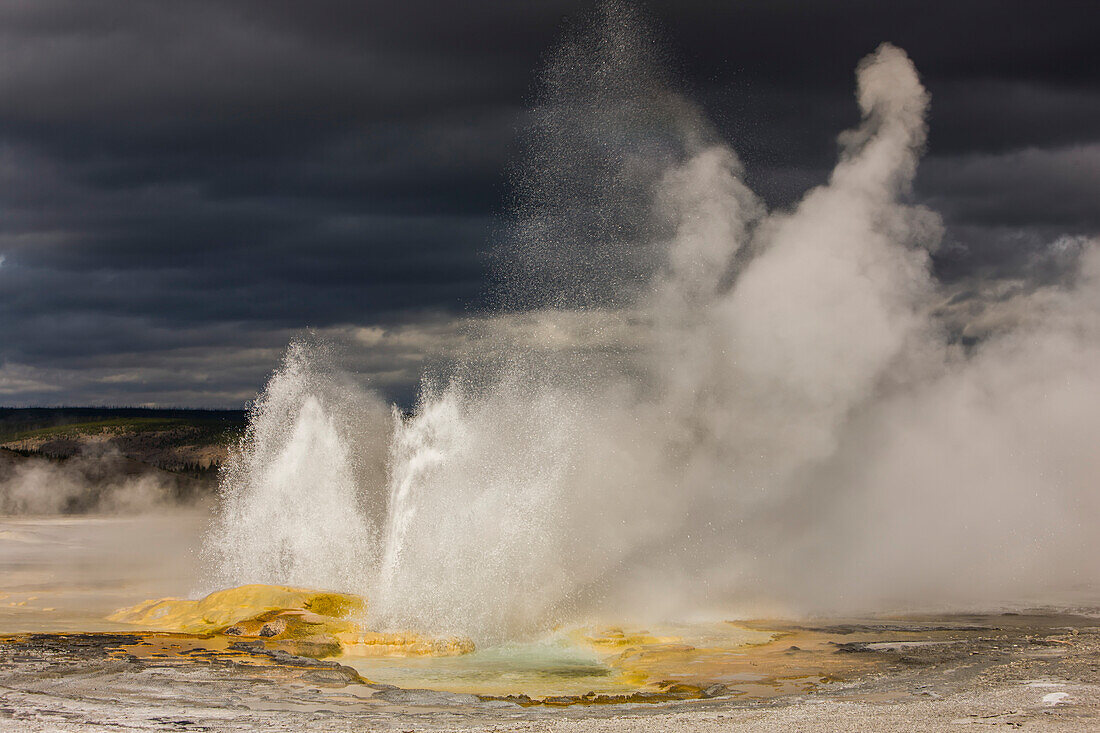 Clepsydra Geysir, der die Erdkruste ausbricht und Wasser- und Dampfstrahlen in die Luft schickt, unter einem grauen, bewölkten Himmel im Yellowstone National Park; Wyoming, Vereinigte Staaten von Amerika