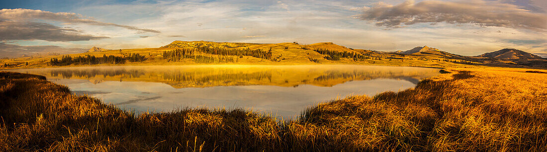 Goldenes Sonnenlicht über Electric Peak und der Gallatin Range spiegelt sich im Swan Lake der Swan Lake Flats im Herbst, Yellowstone National Park; Wyoming, Vereinigte Staaten von Amerika