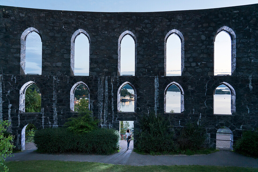 In der Abenddämmerung spaziert ein Besucher durch McCaig's Tower oben in Oban, Schottland; Oban, Argyll, Schottland