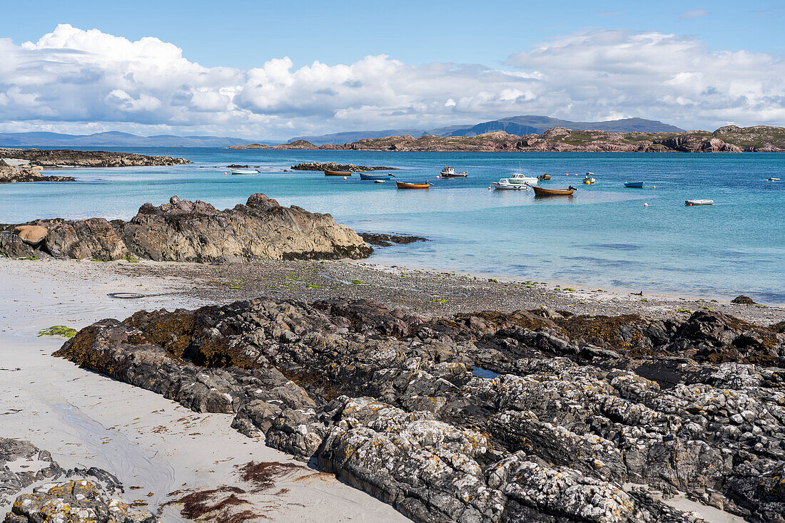 Boats float near the rocky shoreline of the island of Iona, Scotland; Iona, Scotland