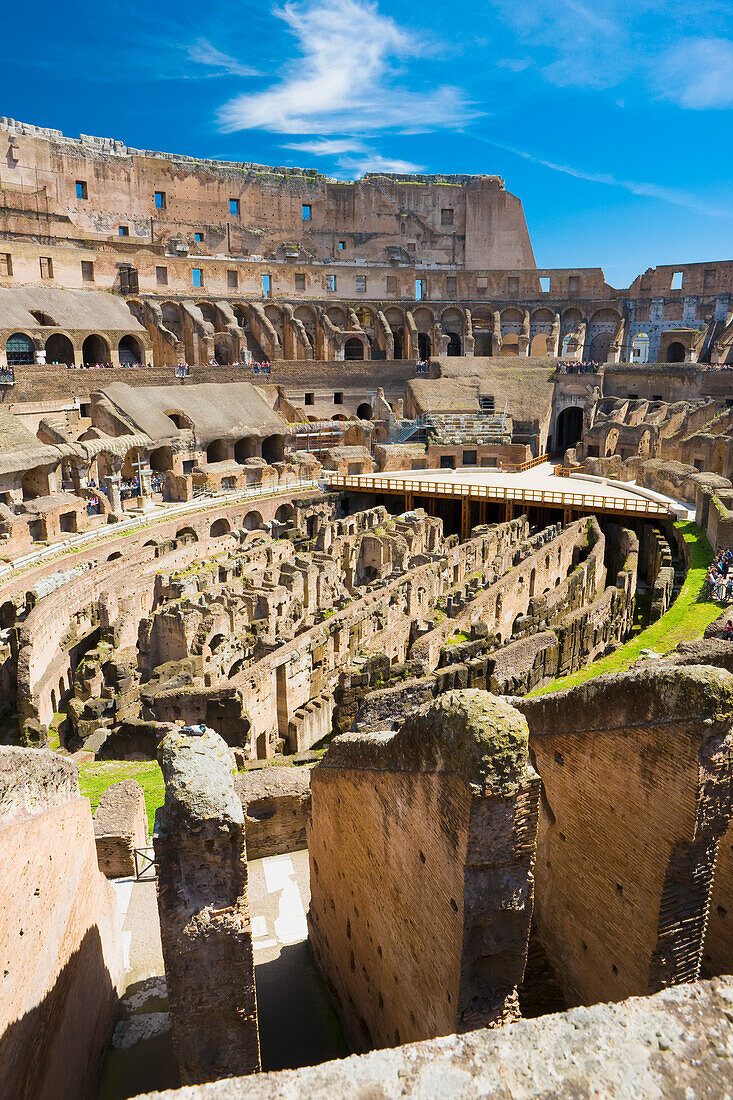 Overview of the interior of the iconic Colosseum against a blue sky with crowds of tourists sightseeing; Rome, Lazio, Italy