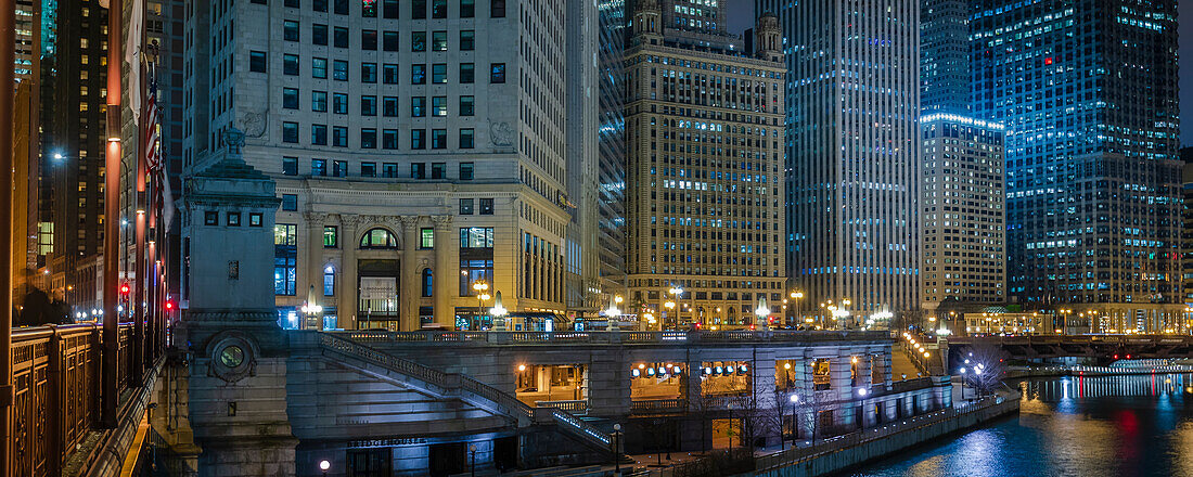 View of the Chicago River crossing the DuSable Bridge and cityscape of iconic office towers, the London Guarantee Building and 35 East Whacker Building in the City of Chicago at night; Chicago, Cook County, Illinois, United States of America