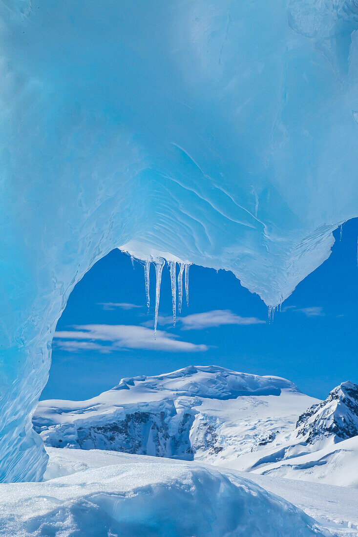 View from under a blue ice archway of an iceberg.