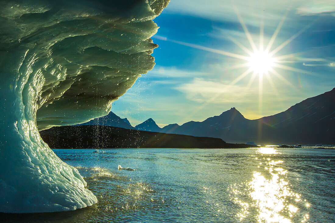 The sun shines brightly on a melting iceberg.