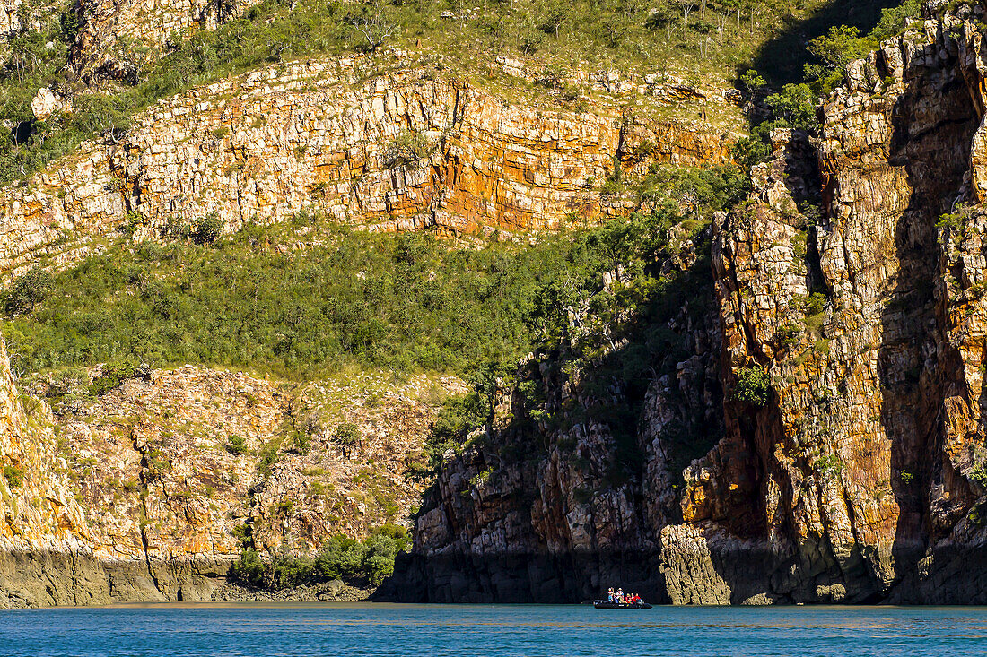 A small boat provides scale against a cliff in Cyclone Bay in the Kimberley Region of Northwest Australia.