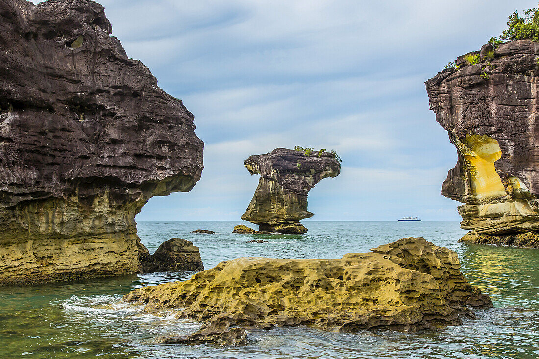 Large sandstone rock formations tower over a Malaysian beach.