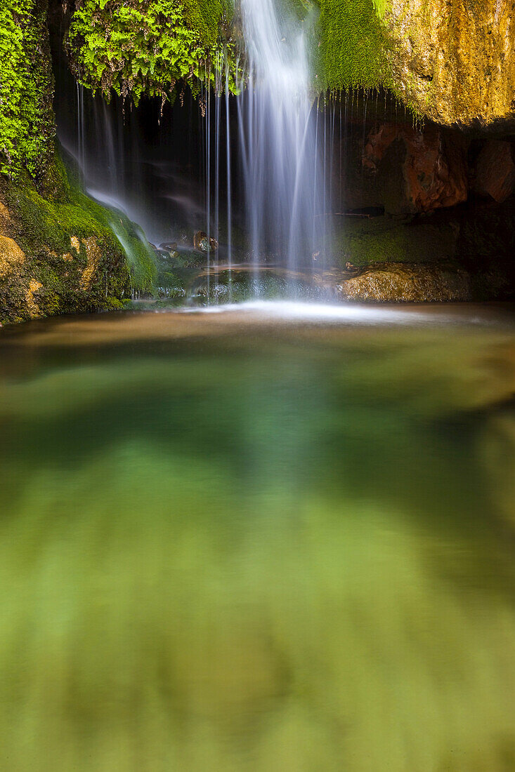 Ein kleiner Wasserfall fließt in ein Becken.