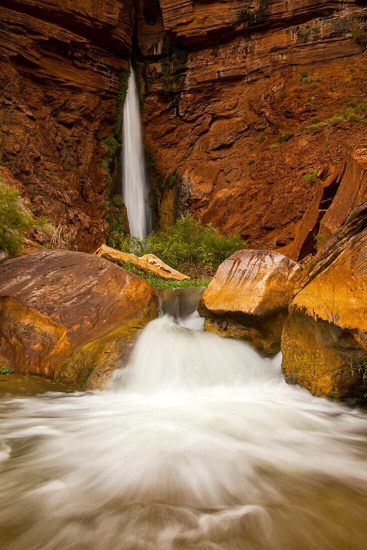 Wasserfall aus einer engen Felsspalte in einem Sandsteinfelsen.