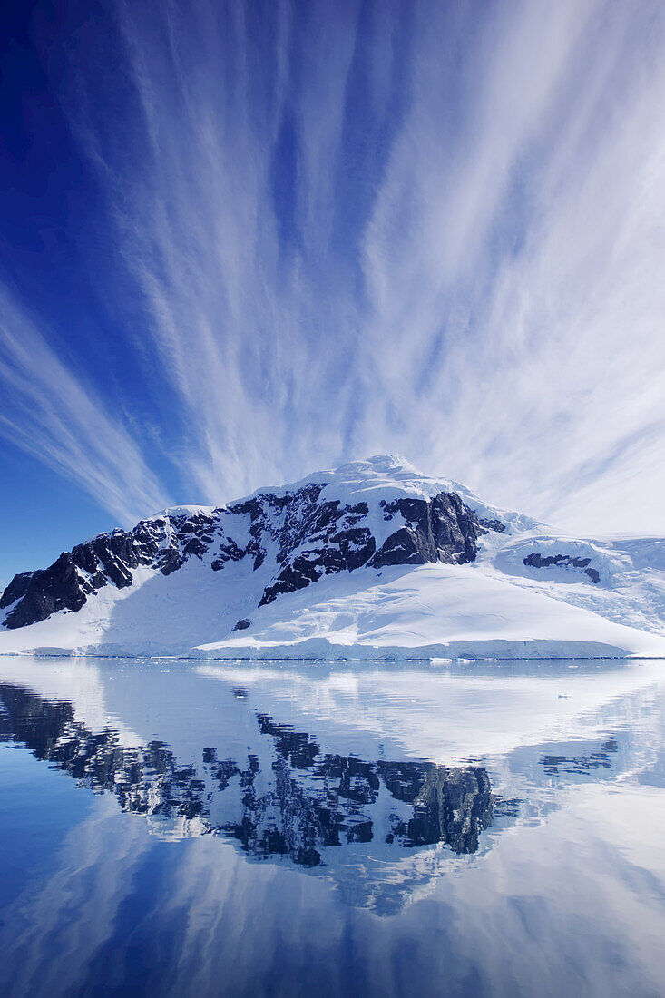 Cirrus clouds over a mountainous coast, and reflection in water.