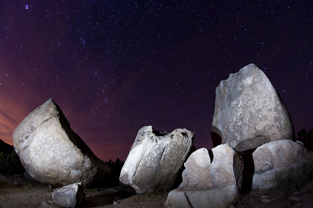 Big boulders and split rocks create mysterious shapes against the starry, night sky; Joshua Tree National Park, California, United States of America