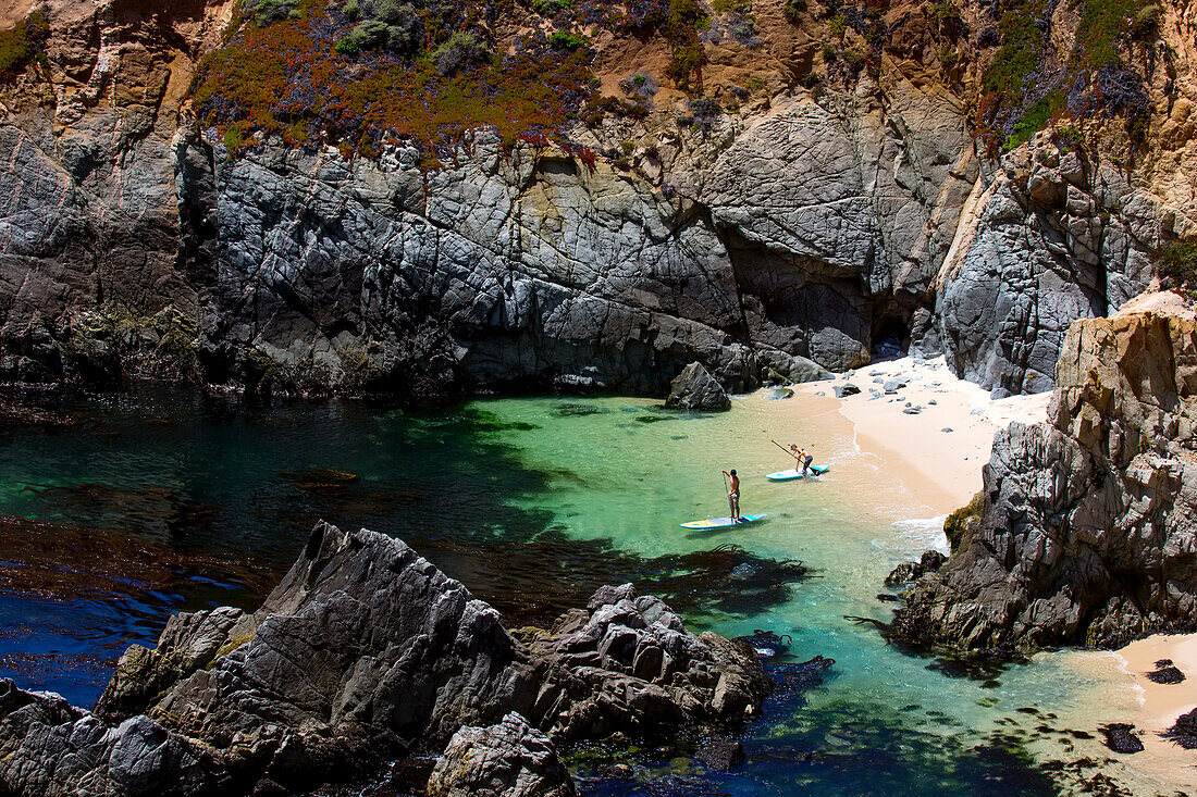 Paddleboarders head out into a secluded bay.