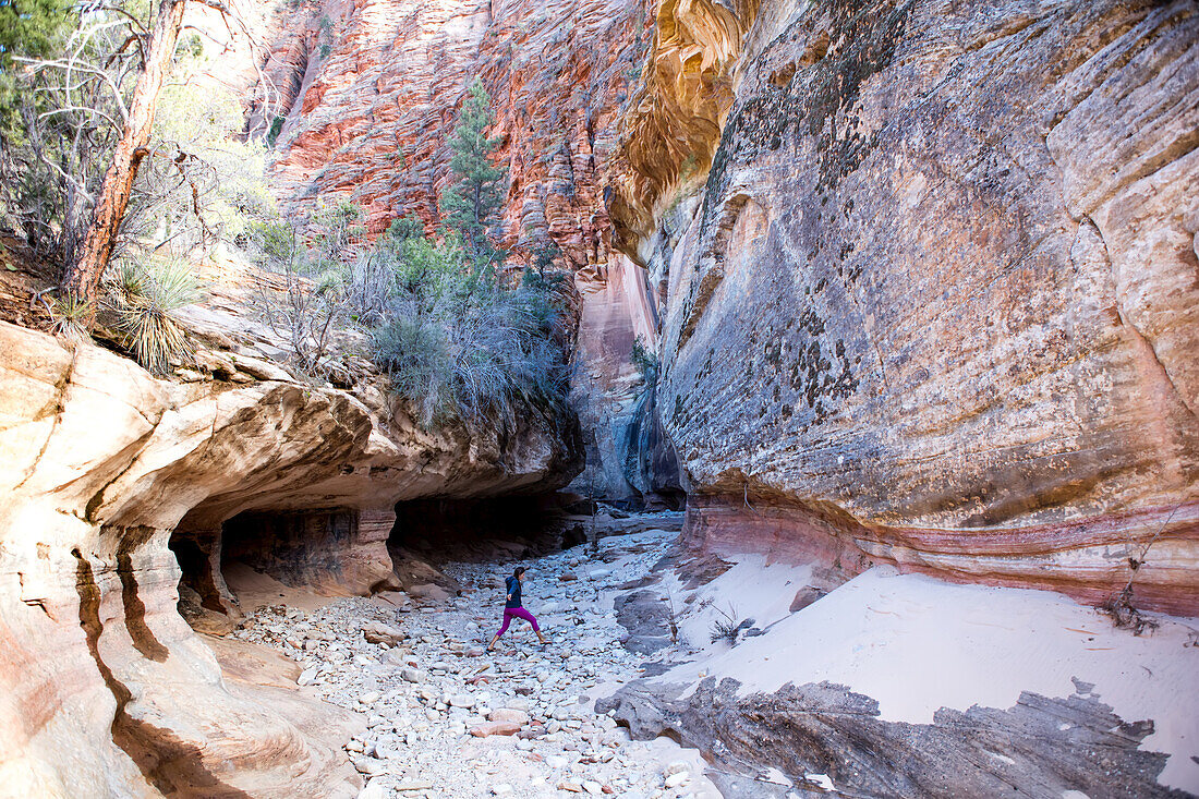 A young woman walks up a riverbed in search of slot canyons in Zion National Park.