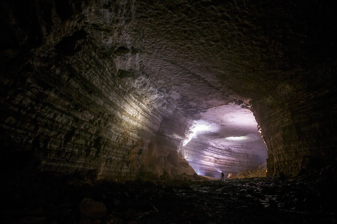 A man shines his headlamp onto the intricate structures on the interior walls of a cave in China.