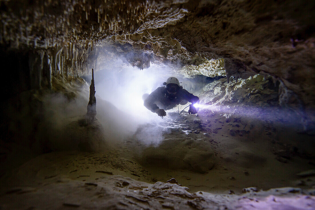 A cave diver passes through a silted out passage.