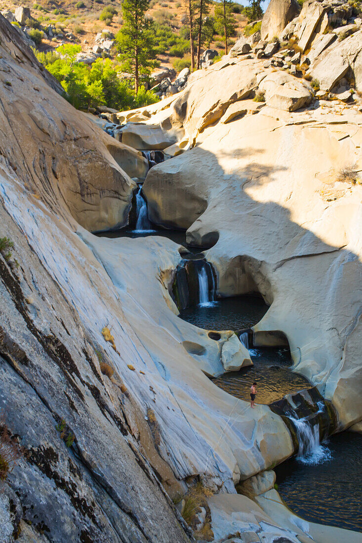 A hiker stands on the edge of one of the waterfalls at the Seven Teacups.