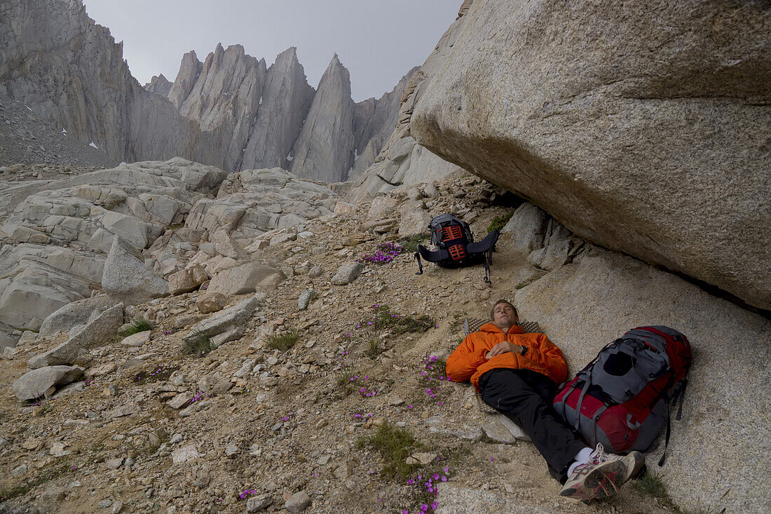 A climber takes shelter from the rain on the difficult approach to climb Mount Whitney.