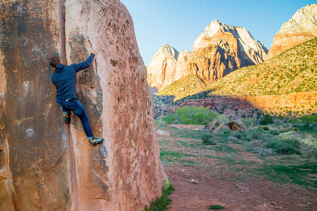 A man bouldering on the sandstone walls of Zion National Park.