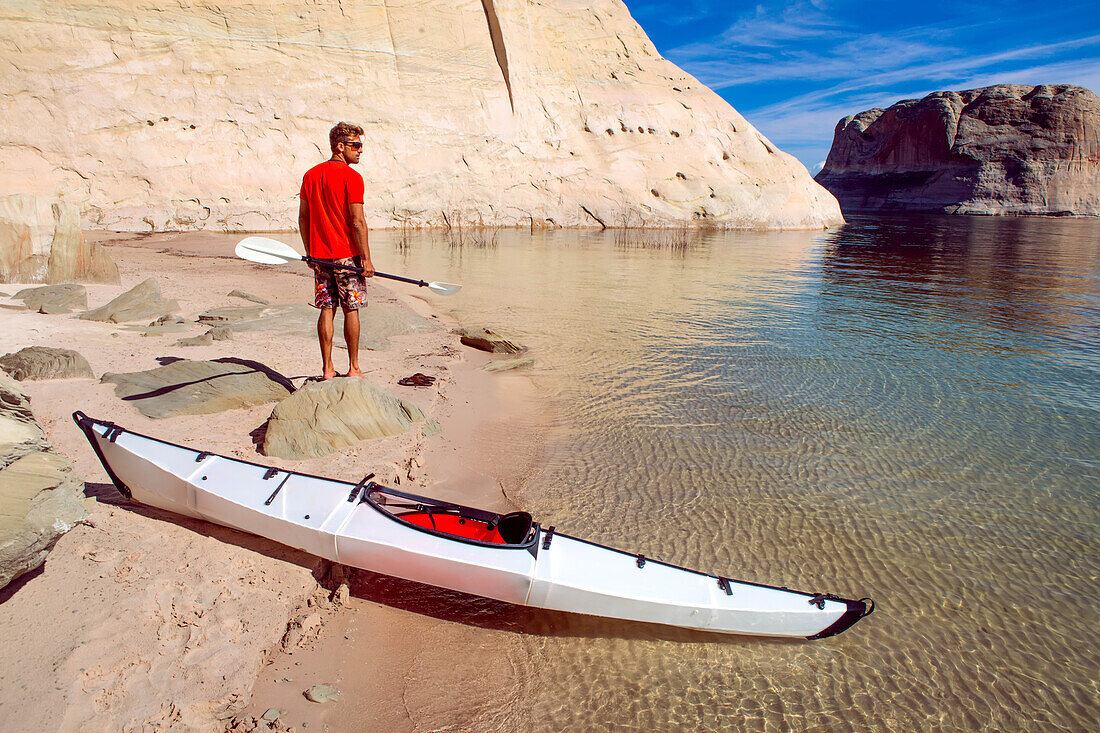 A man gets out of his sea kayak to inspect a remote beach.