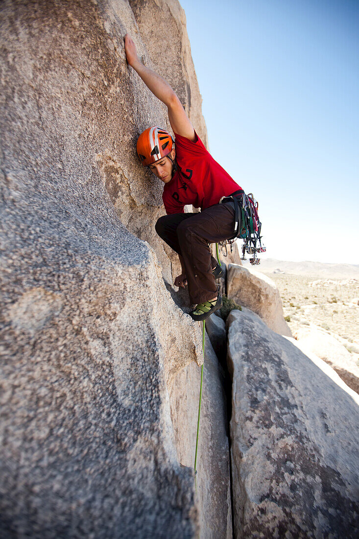 A climber balances his body to reach a higher hold.