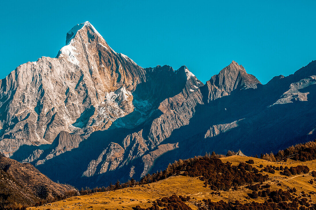 Rugged mountainous terrain of Mount Siguniang under a bright blue sky, Siguniang National Park; Ngawa Prefecture, Sichuan, China