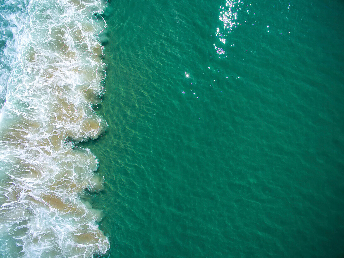 Türkisblaues Wasser bricht sich am Sand des Zuma Beach.