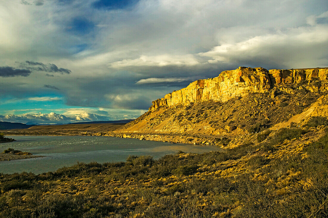 Rio La Leona fließt durch die patagonische Steppe mit ihrer kargen Landschaft und der berühmten Nationalstraße 40 im böigen Sonnenlicht bei El Calafate in der Provinz Santa Cruz; Patagonien, Argentinien