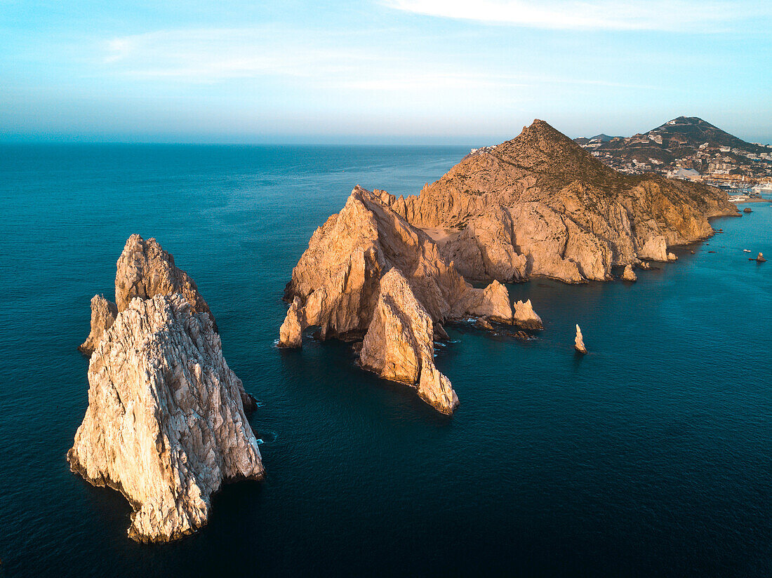 Dramatic rock formations on the southern tip of the Baja Peninsula called Lands End from the air at sunset with the resort city of Cabo San Lucas in the background; Cabo San Lucas, Baja California Sur, Mexico