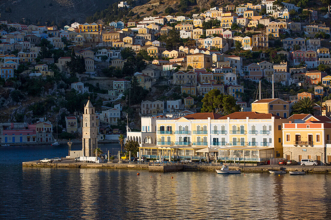 Symi Uhrenturm und sonnenbeschienene Gebäude am Hafen von Gialos, Insel Symi (Simi); Dodekanes-Inselgruppe, Griechenland