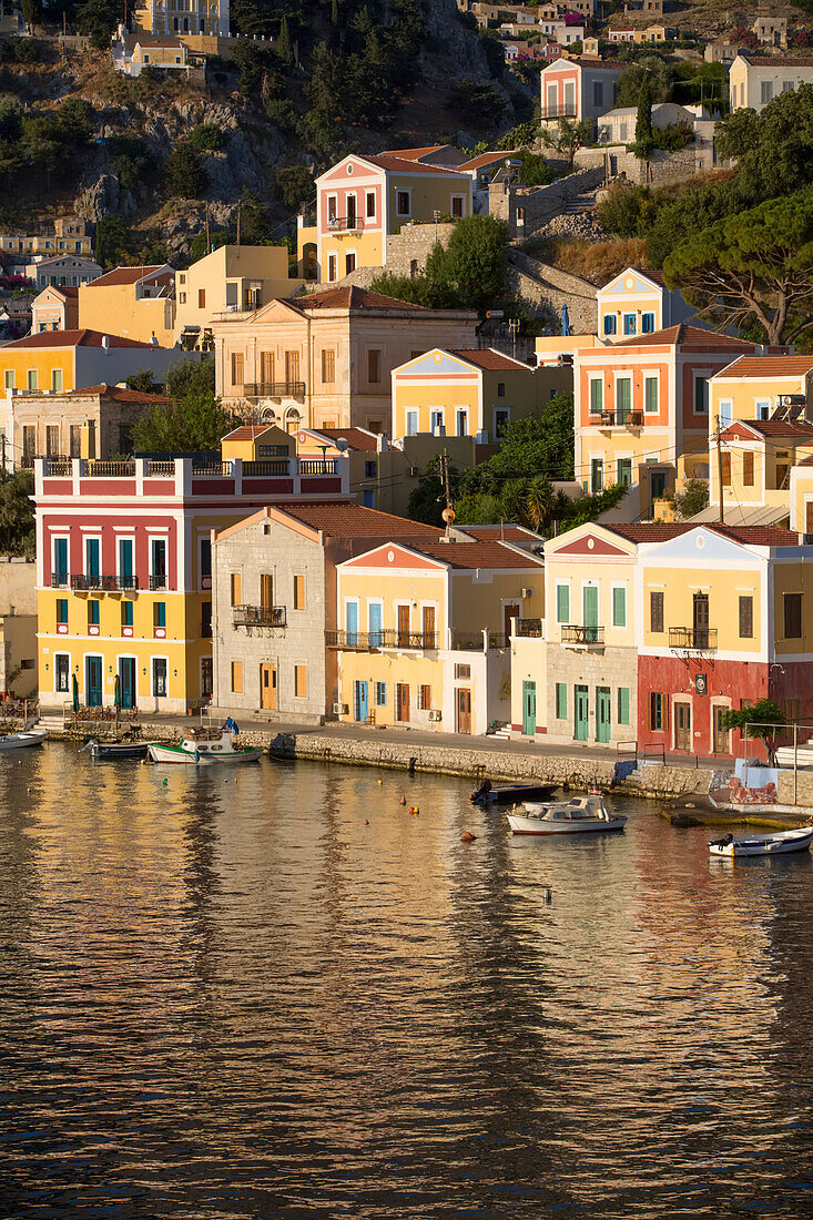 Warm sunlight on the colorful buildings along the waterfront in Gialos Harbor, Symi (Simi) Island; Dodecanese Island Group, Greece